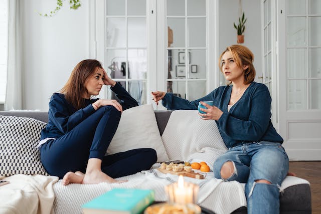 Two women sitting on the couch talking